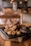 A cast iron pan filled with grilled meat and caramelized onions rests on a wooden platter, set on a rustic wooden table. The background features blurred lights and furniture, creating a cozy, ambient atmosphere.