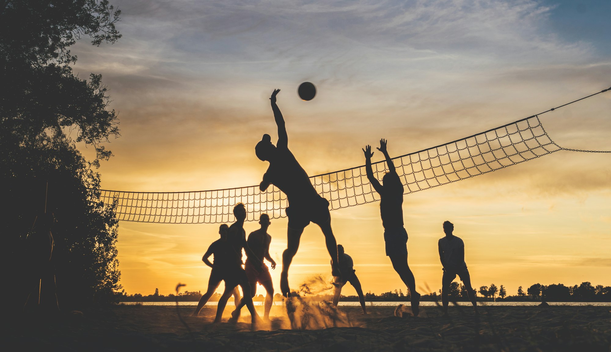 A group of friends play beach volleyball while the sun is setting. Taken on a warm summer evening at the Loosdrechtse Plassen in the Netherlands.