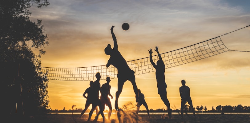 silhouette of people playing basketball during sunset