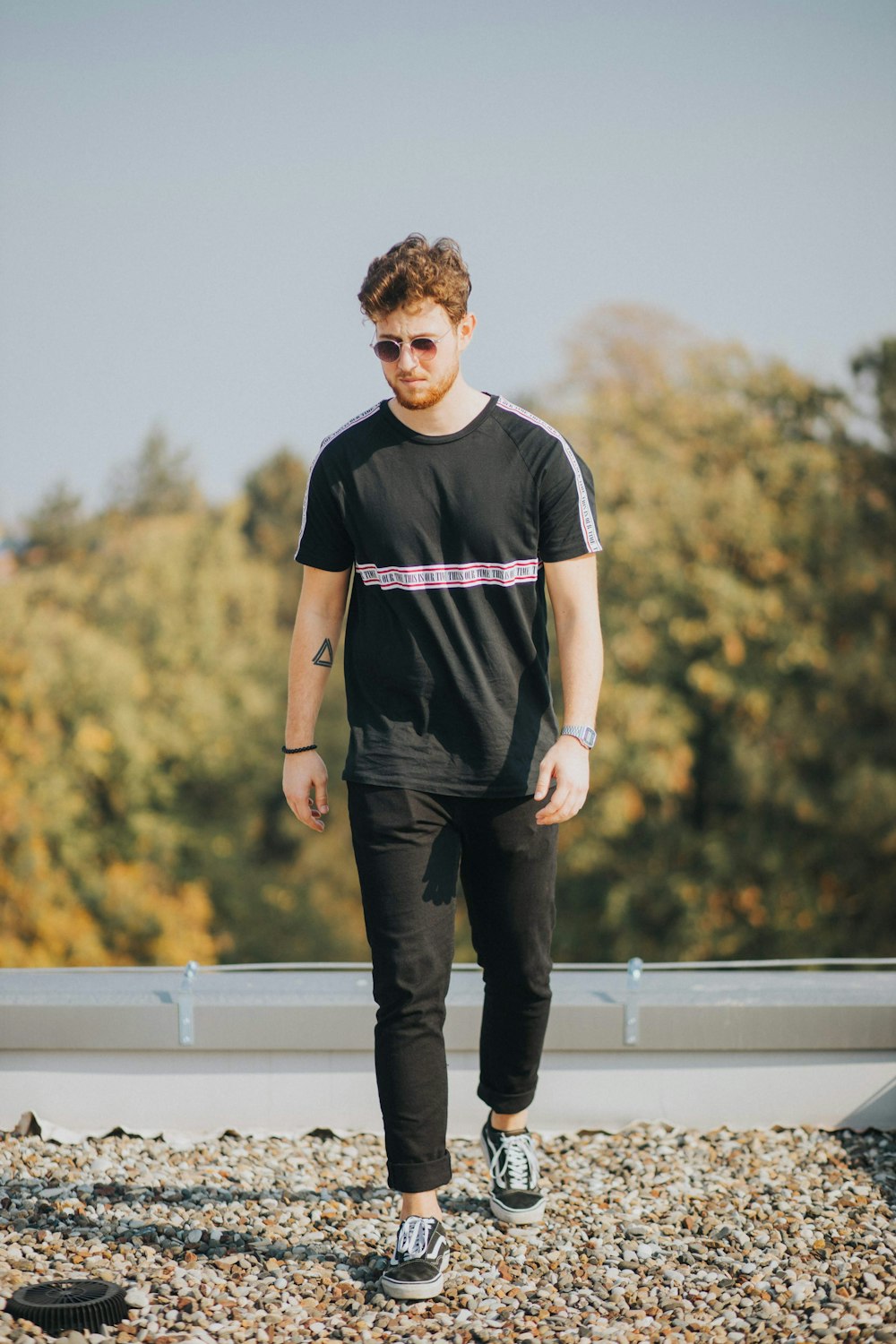 man in black and white adidas crew neck t-shirt and black pants standing on white