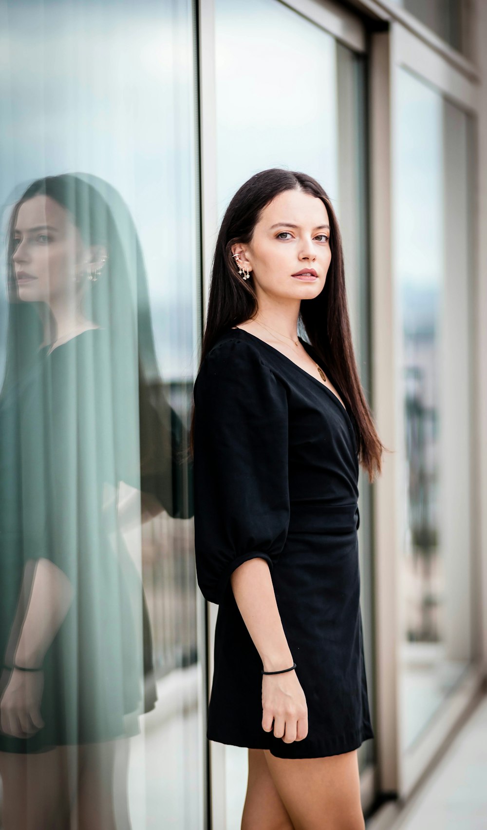 woman in black long sleeve shirt standing beside glass window