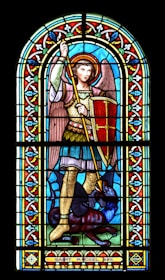 A close-up of a stained glass window depicting St. Michael.