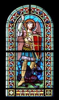A close-up of a stained glass window depicting St. Michael.