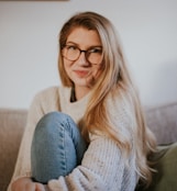 woman in blue denim jeans and white sweater sitting on gray sofa