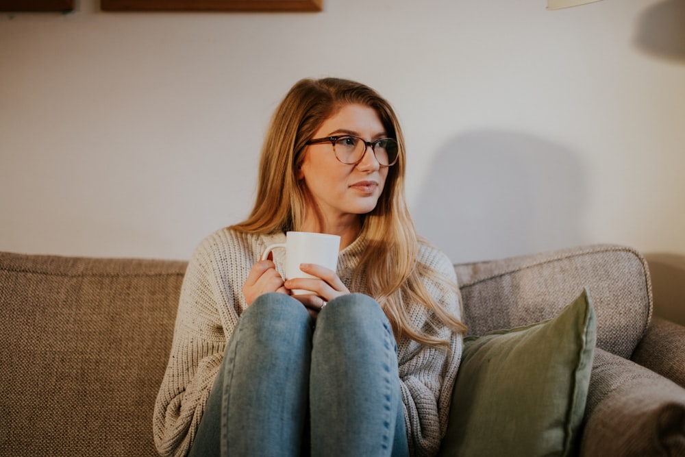 woman in blue denim jeans sitting on gray sofa