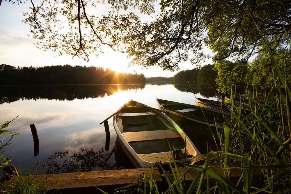 barco branco e marrom no lago durante o pôr do sol