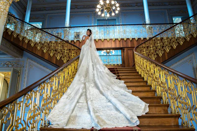 Elegant black and gold-themed cinematic frame showing a bride walking down a grand staircase.