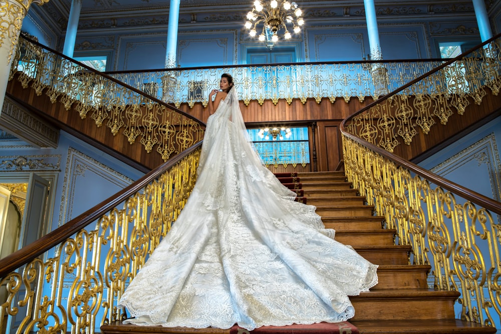 mujer en vestido de novia blanco de pie en la escalera