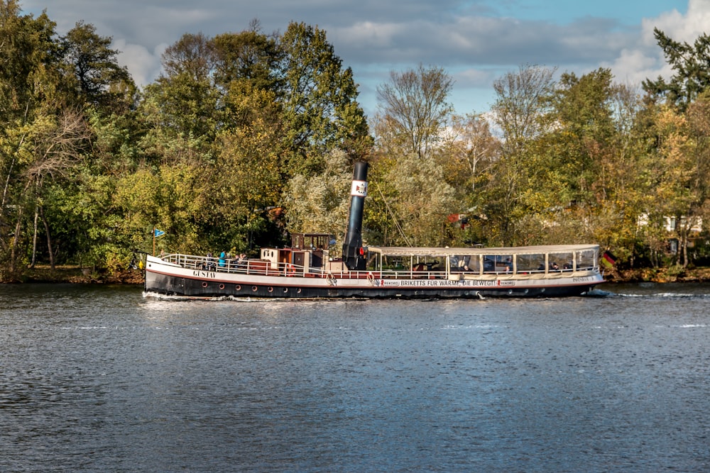 white and brown boat on body of water near green trees during daytime