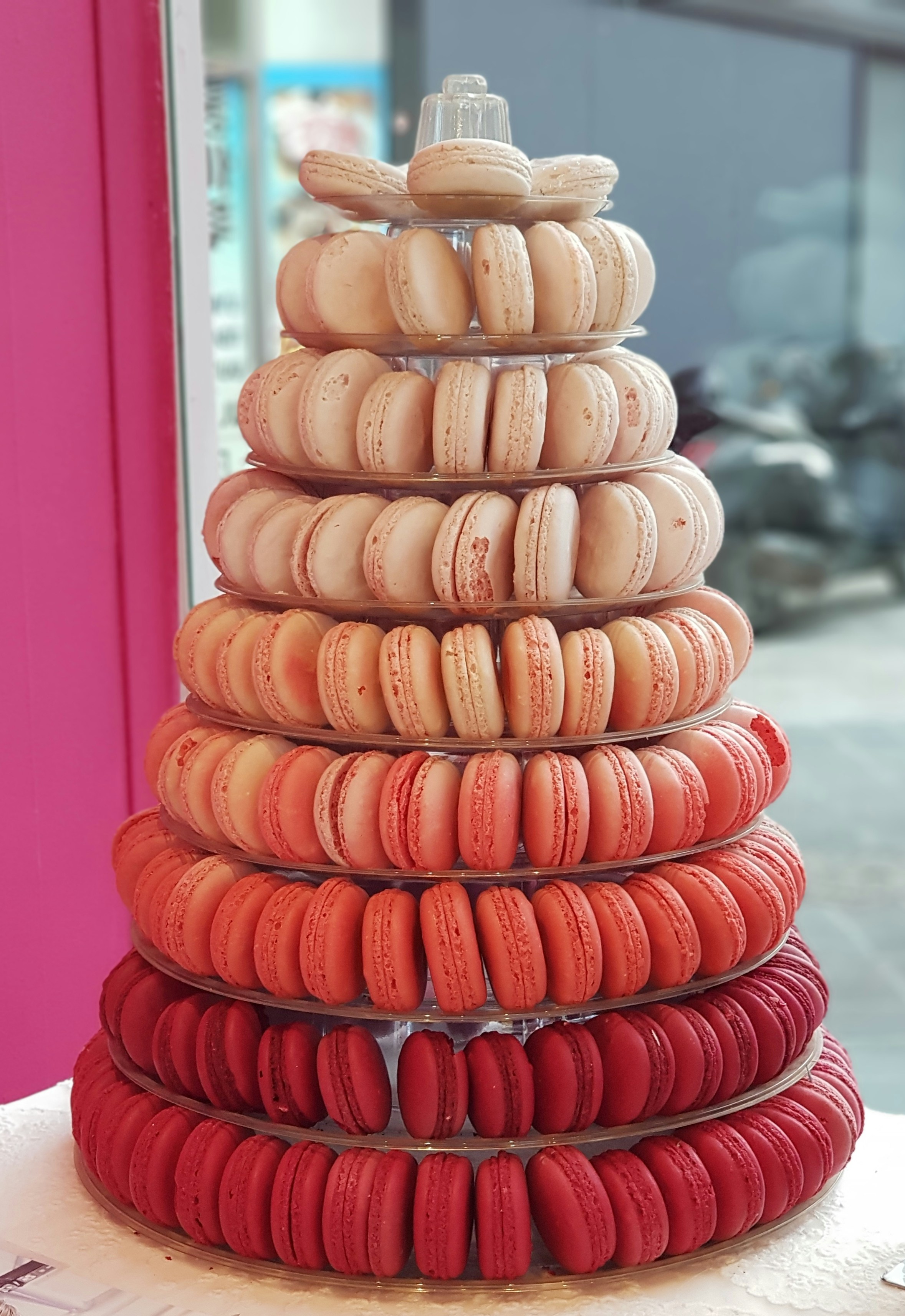 Colorful French macarons in pastel shades stacked on a white ceramic stand in bright studio