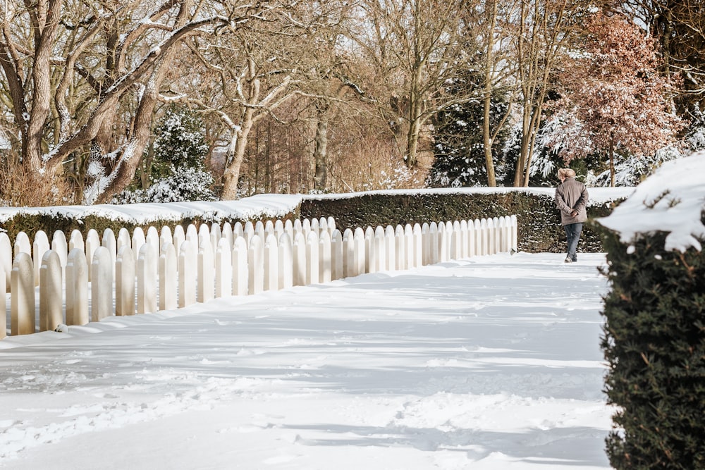 Person in schwarzer Jacke, die tagsüber auf einem schneebedeckten Weg geht