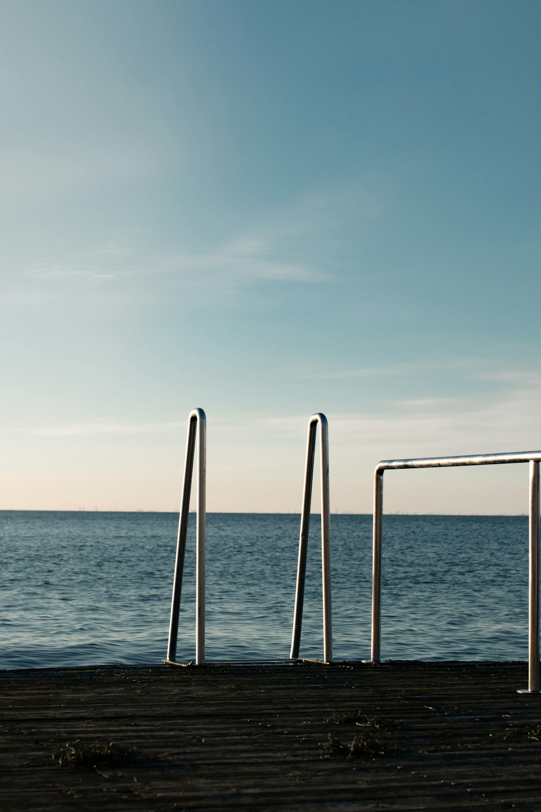 white metal railings on blue sea under white sky during daytime