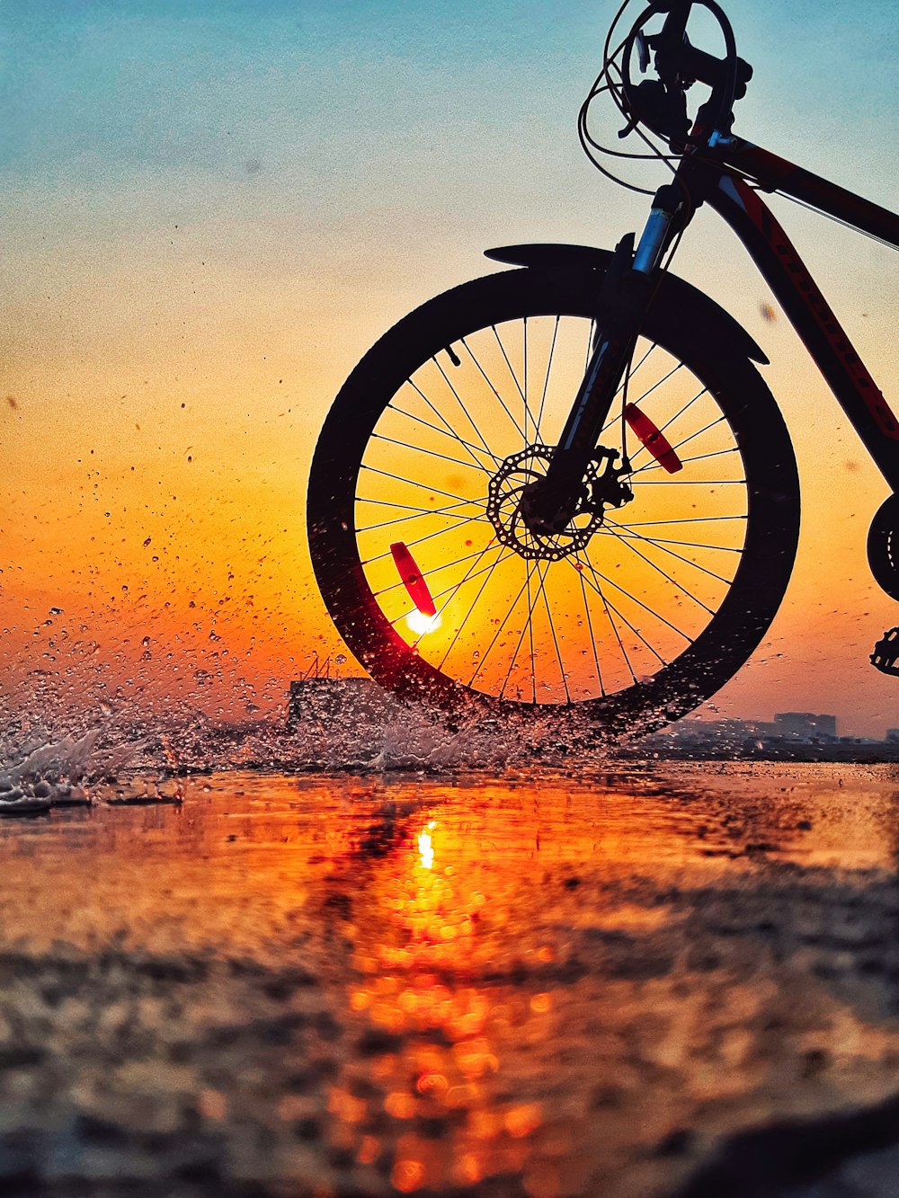 Mountain bike wiel in de zee met zonsondergang