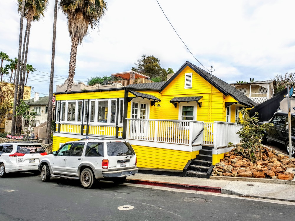 white suv parked beside yellow and green house during daytime