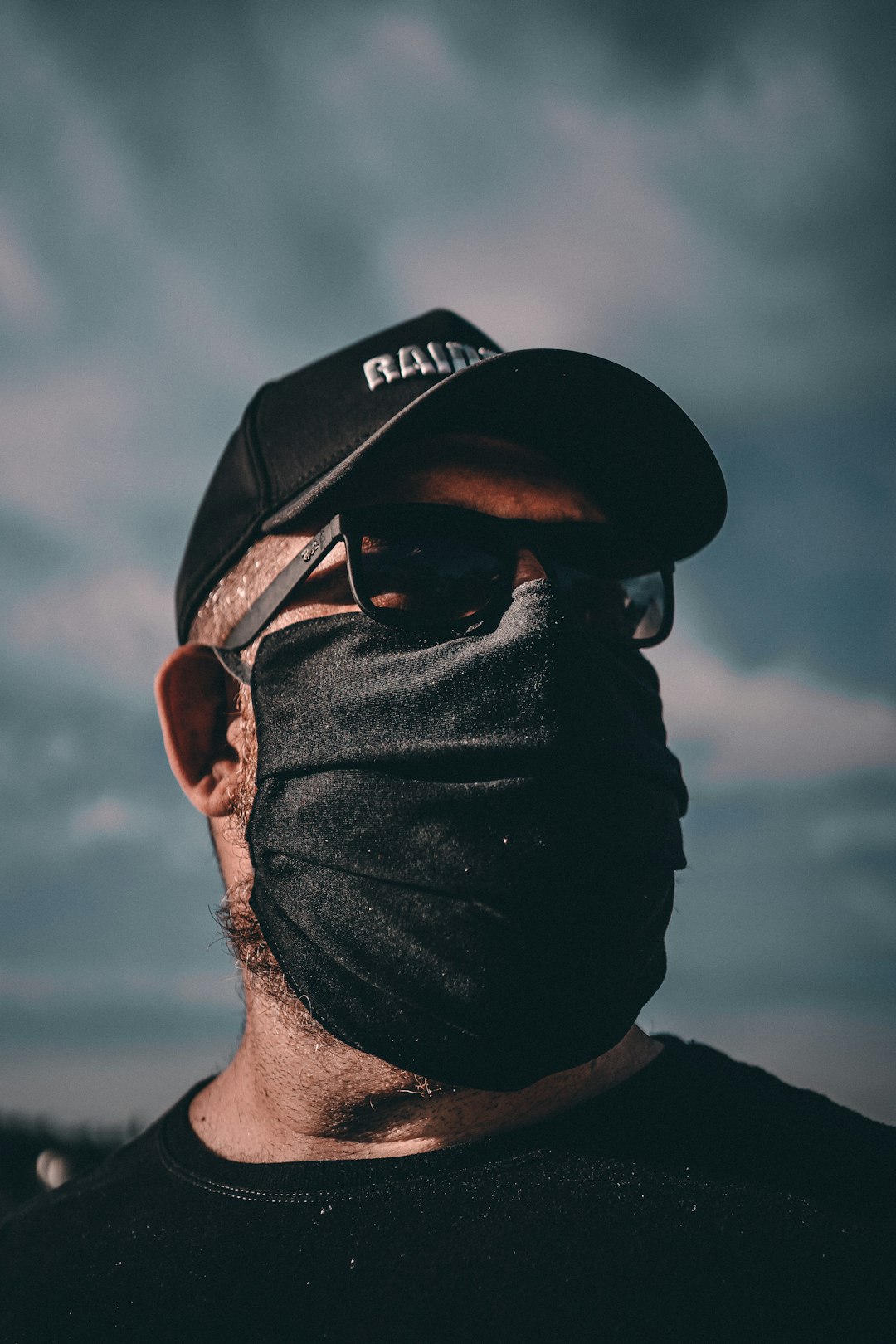 man wearing black fitted cap and black sunglasses