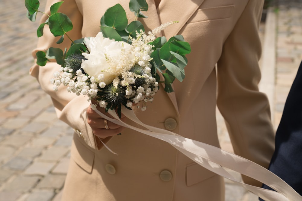 woman in beige blazer holding white flower bouquet