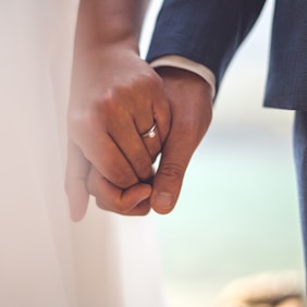 man in black suit jacket holding hands with woman in white dress