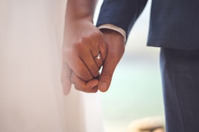man in black suit jacket holding hands with woman in white dress