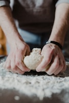 A close-up of hands kneading dough on a floured surface.