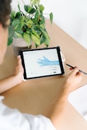 person holding black ipad on brown wooden table
