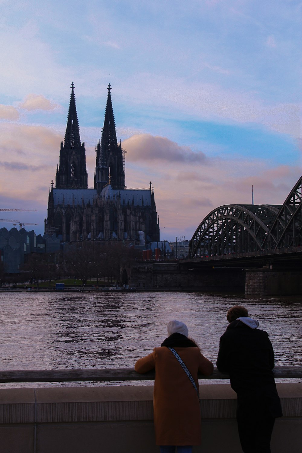 man and woman standing on bridge near body of water during daytime