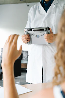 Close-up of hands holding a tablet displaying clinical research data in a rural setting.