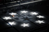 A shimmering ice rink illuminated under soft blue lights.