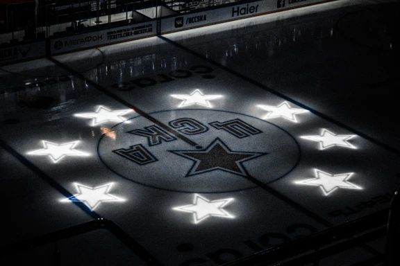 A sleek ice hockey rink under bright lights with a player poised for a powerful shot.