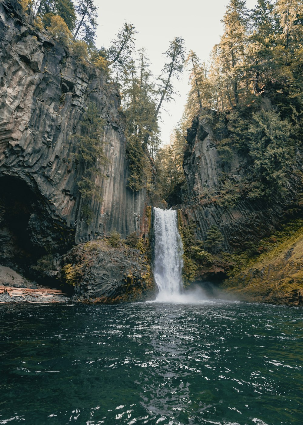 water falls between rocky mountain during daytime