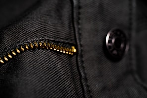 Close-up of a black hoodie with rose gold zipper detail under soft lighting