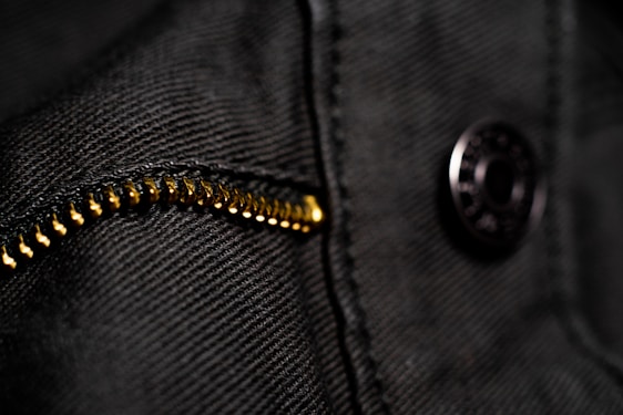 A close-up shot of a luxurious rose gold zipper on a sleek black garment, highlighting premium fabric texture.
