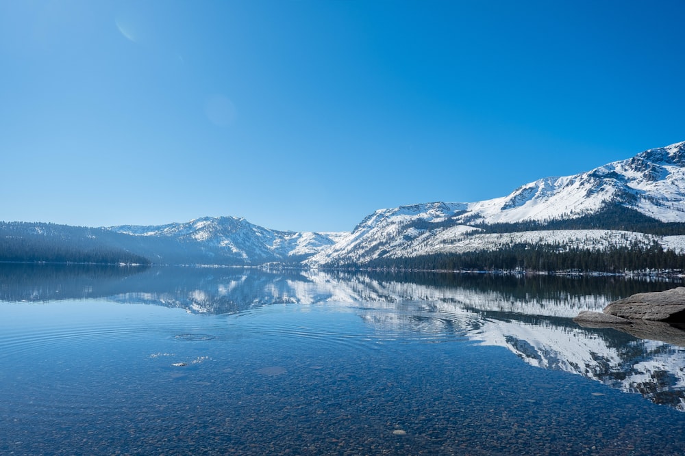 snow covered mountain near body of water during daytime