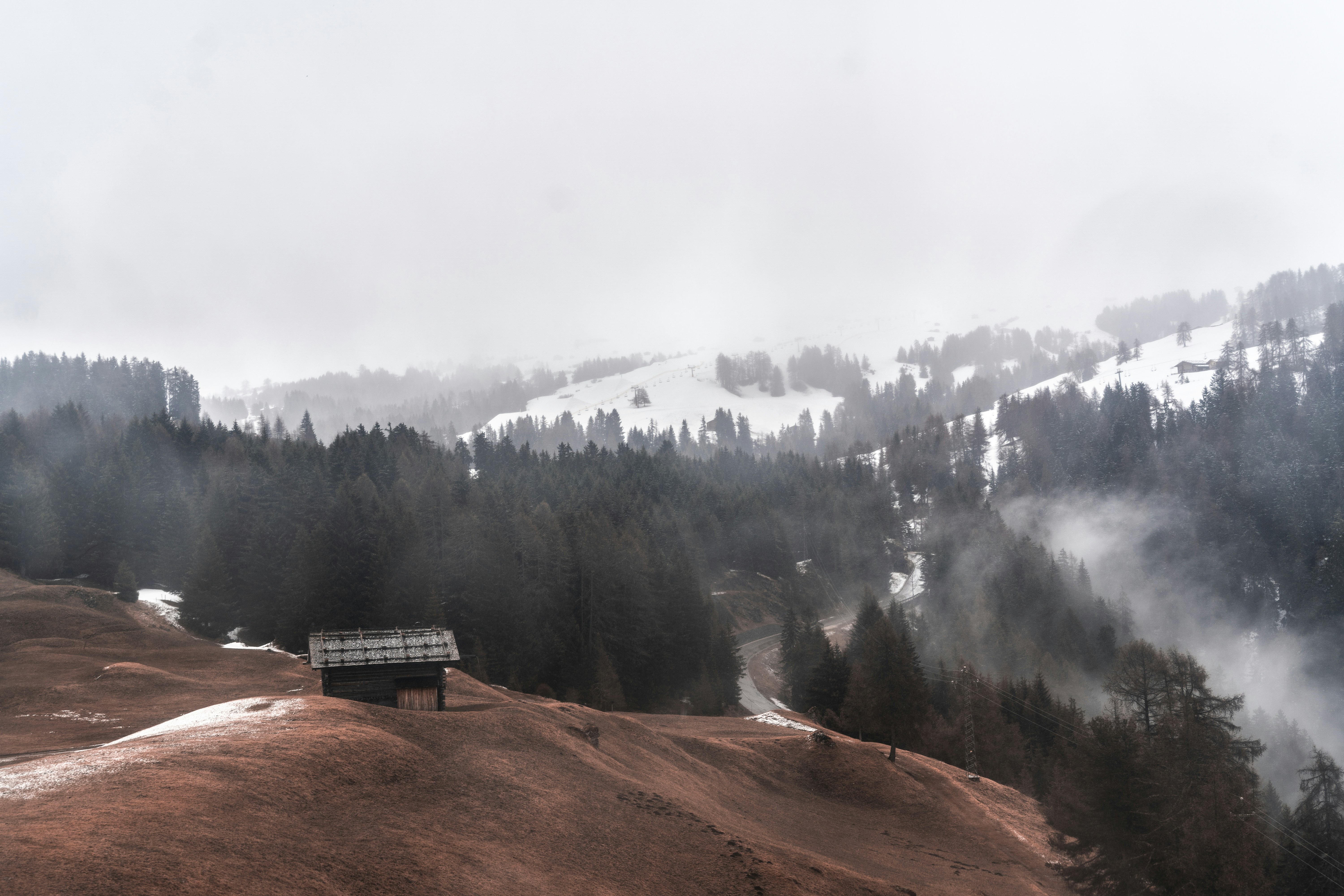 white wooden house on brown field near green trees and mountain during daytime
