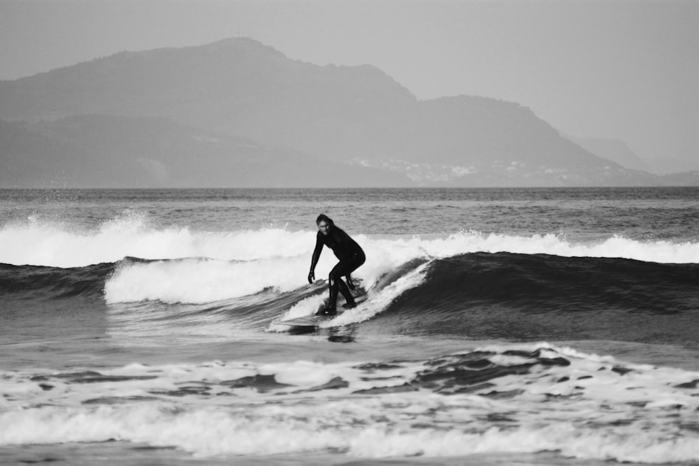 grayscale photo of man surfing on sea waves