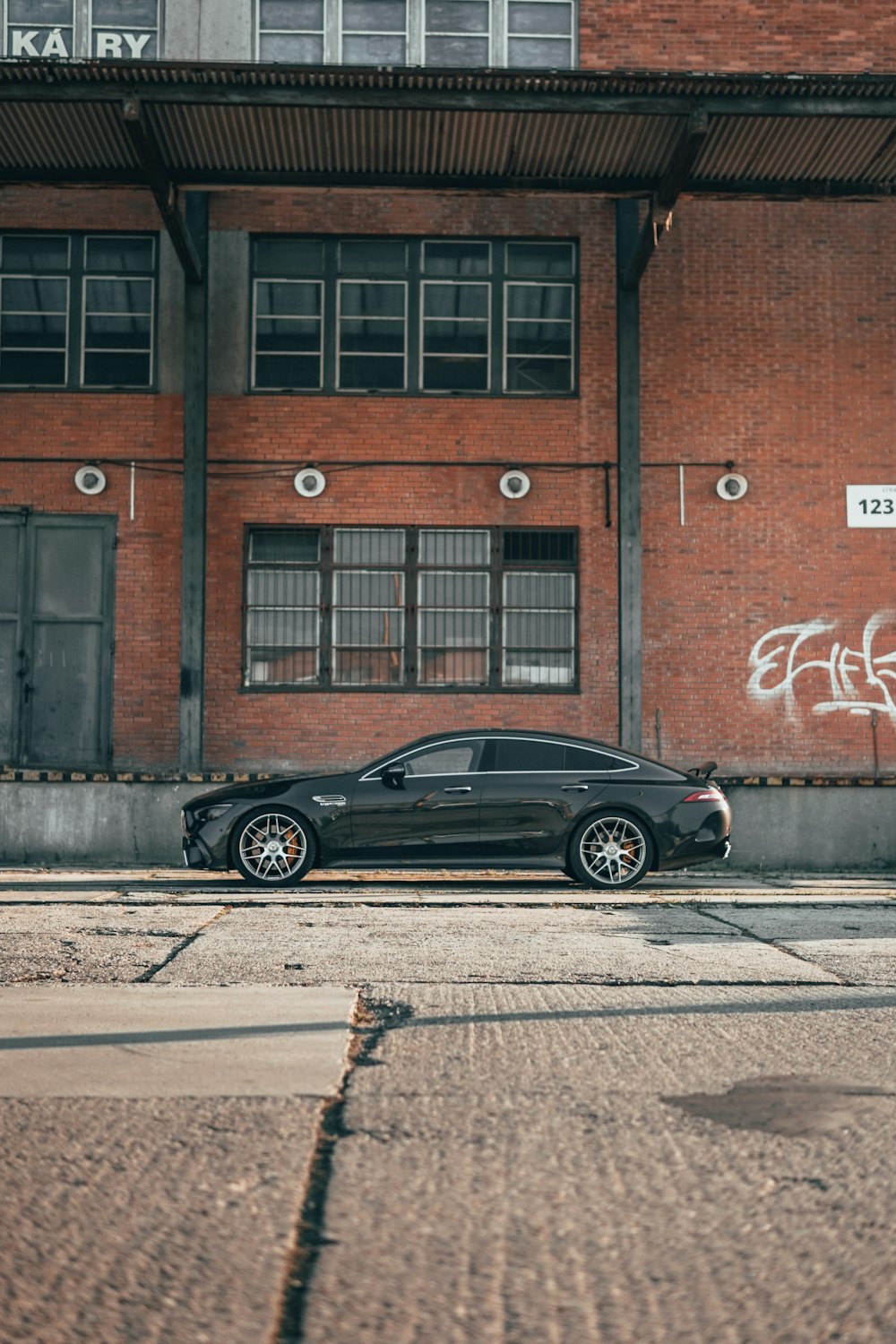 black sedan parked beside brown concrete building during daytime