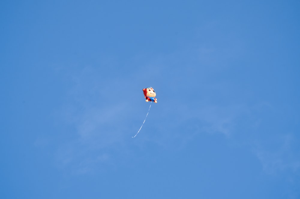 red and white kite flying under blue sky during daytime