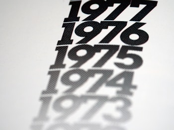 A series of bold, black numbers arranged vertically on a white background, each following the previous year chronologically: 1977, 1976, 1975, 1974, and 1973. The numbers appear to fade into the background, creating a shadow effect.