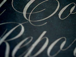 Elegant lettering tattoo in flowing script with subtle red accents on smooth skin