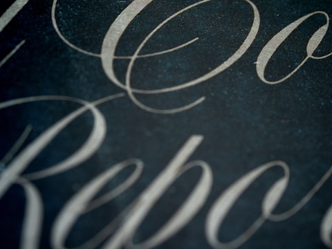 Elegant, cursive script in a light color is set against a dark background, creating a sophisticated and refined aesthetic.