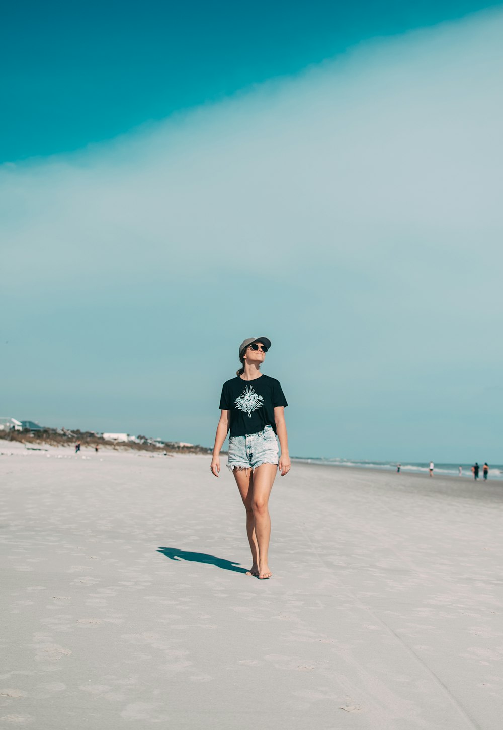 woman in black and white t-shirt and blue denim shorts standing on beach during daytime