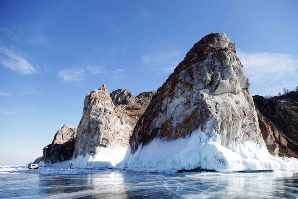 brown and white rock formation on body of water under blue sky during daytime