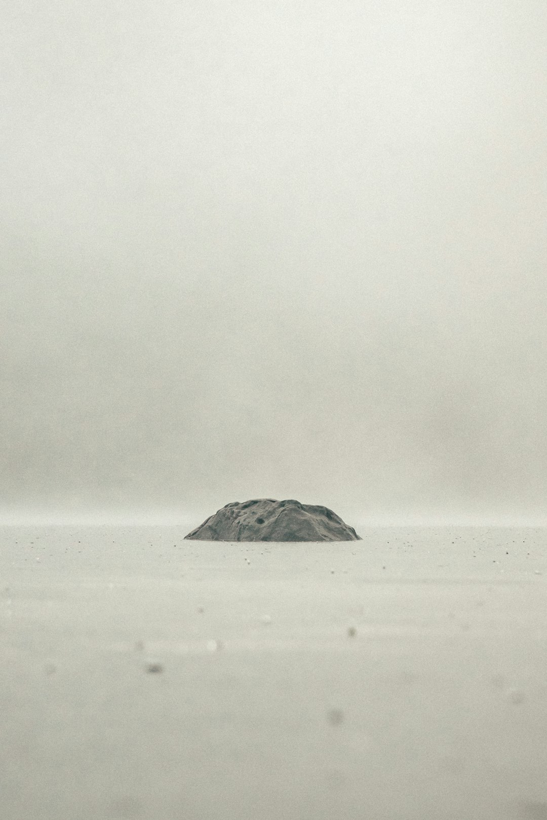 black rock on white sand during daytime