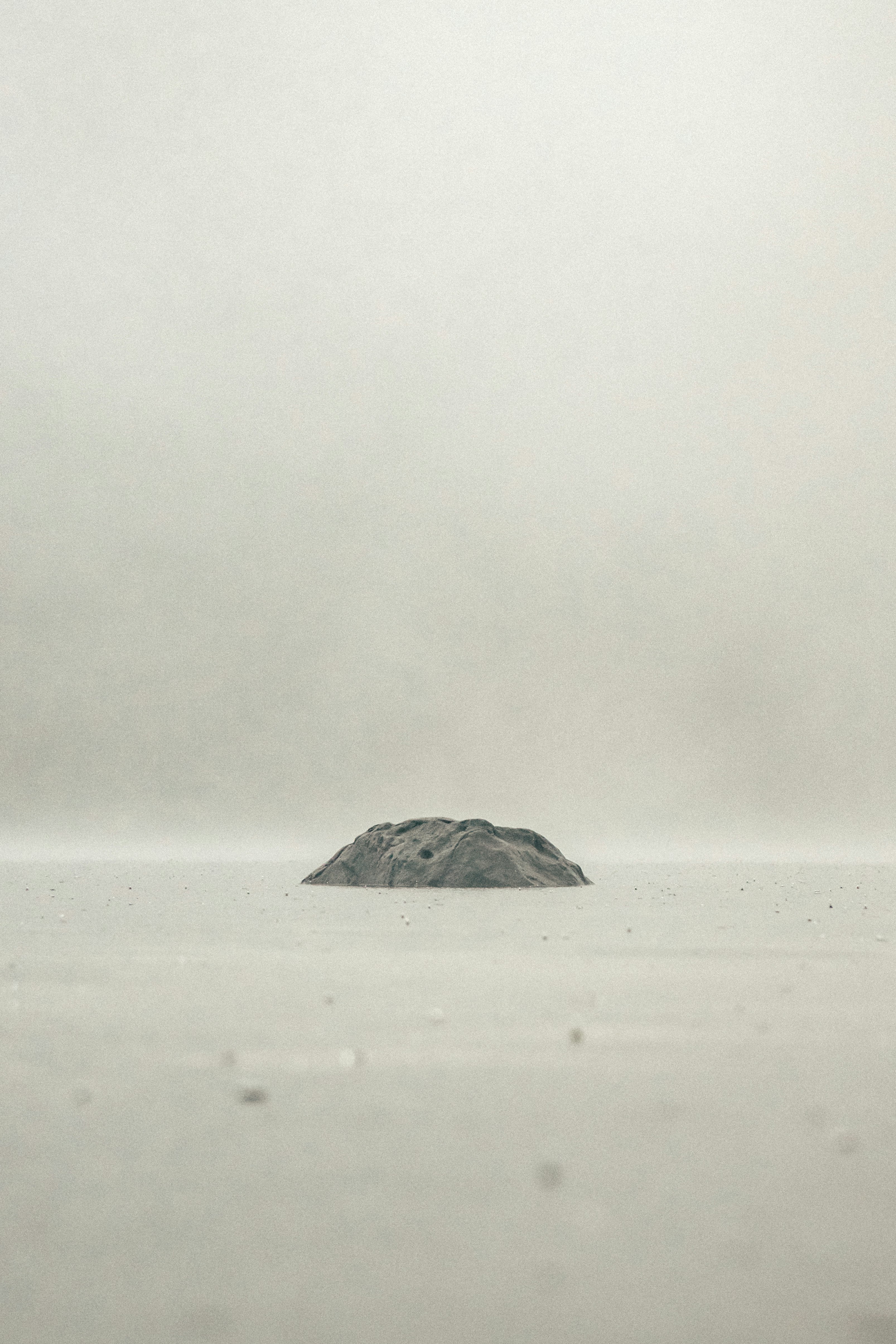 black rock on white sand during daytime