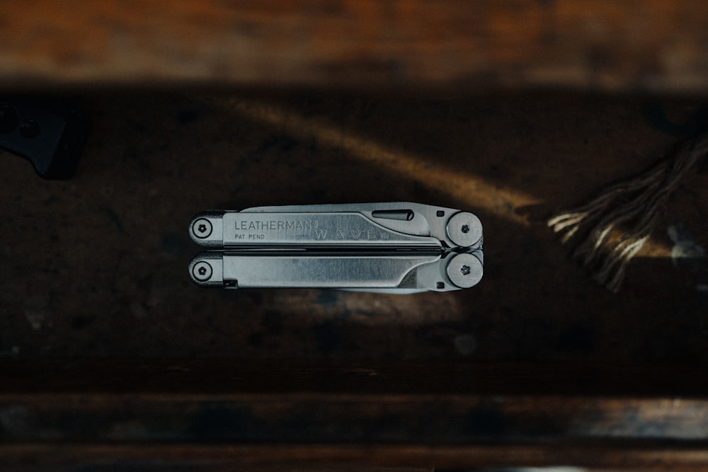 silver multi tool on brown wooden table