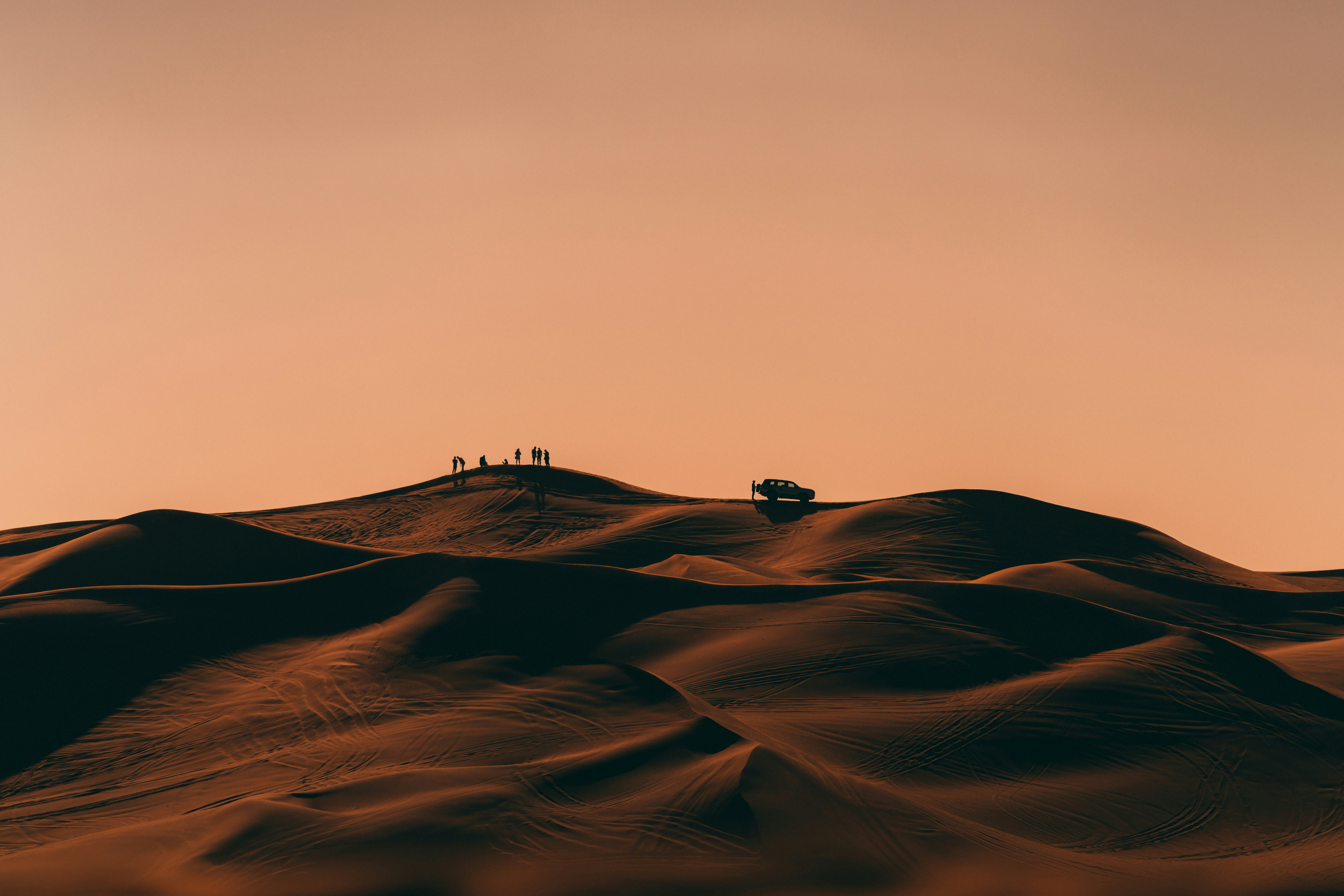 Silhouette of tourists and their guide in the Dubai desert while on Safari.