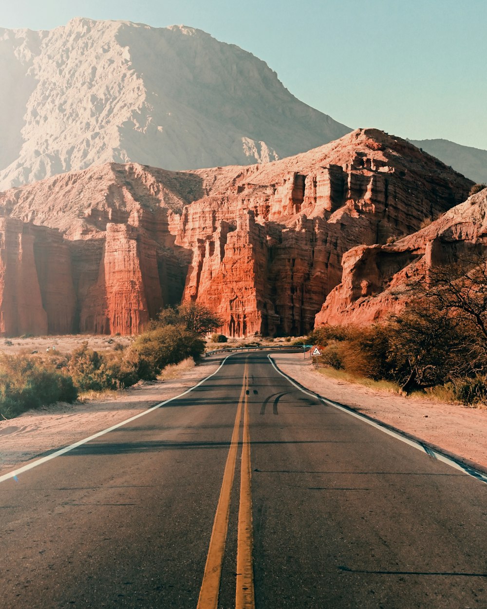 gray asphalt road near brown mountain during daytime