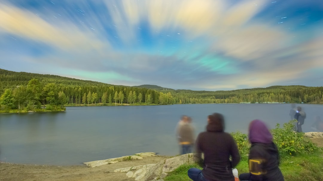 man and woman sitting on rock near lake during daytime