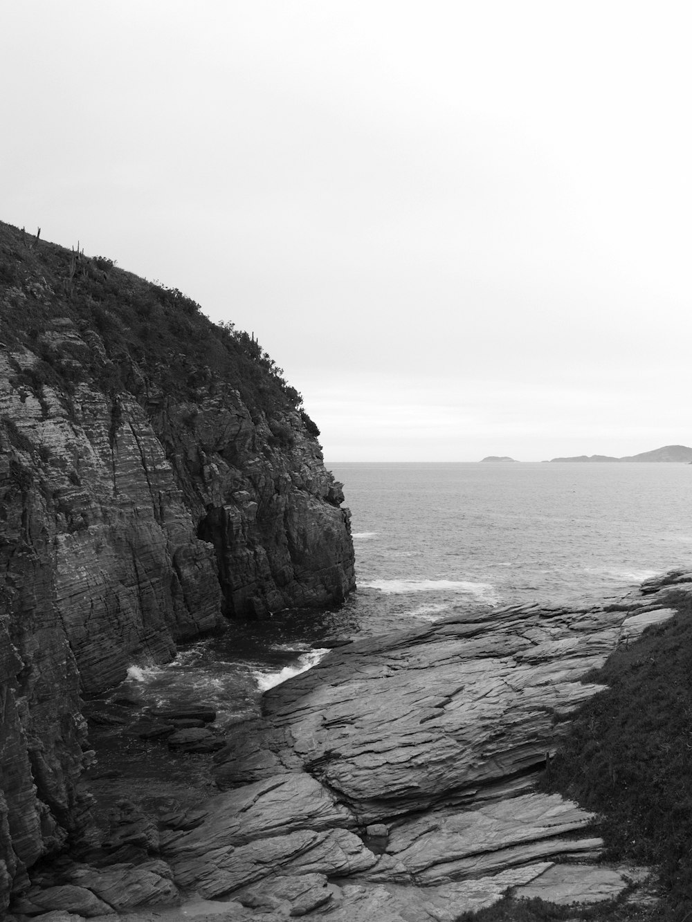 gray rocky mountain beside body of water during daytime