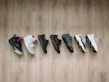 A lineup of basketball shoes from Nike, Jordan, and Adidas displayed on a wooden floor.