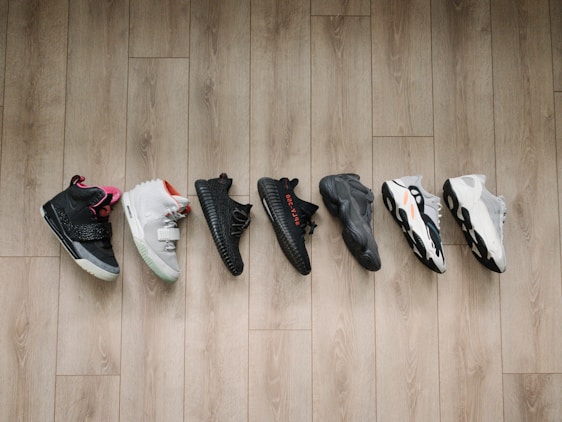Photo of a variety of running and casual sneakers neatly arranged on a wooden floor.